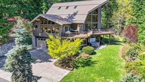 A two-story house with a deck, surrounded by trees and a well-maintained lawn.