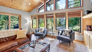 A spacious living area with a high ceiling, large windows, a leather sofa, and a coffee table.