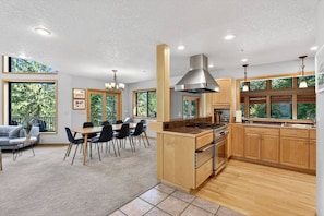 A modern kitchen with wooden cabinets, a central island, and a dining area with a table and chairs.