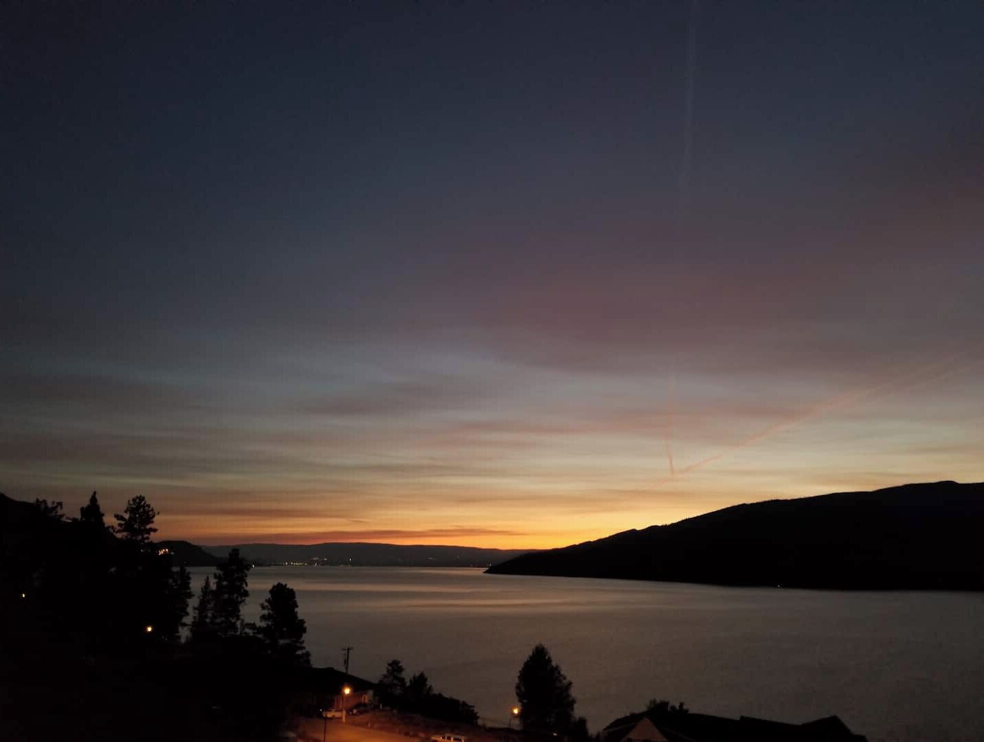 A calm lake at dusk with a clear sky.