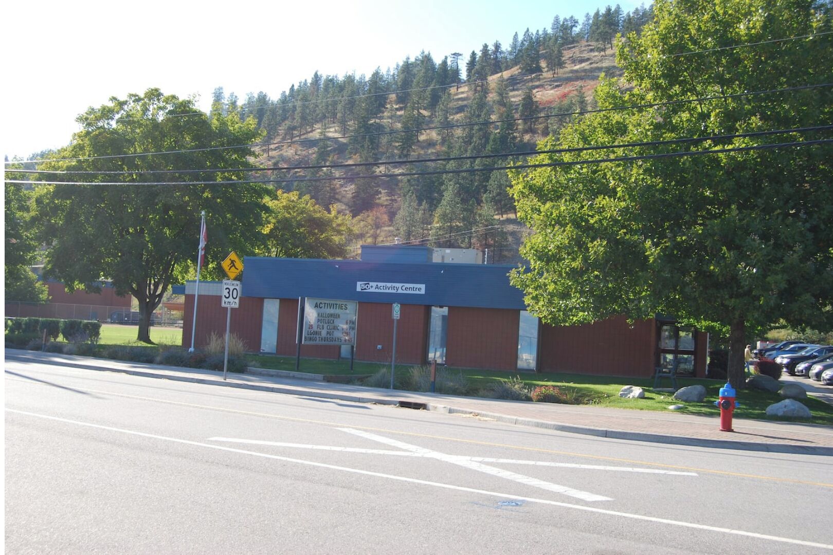 A building with a sign indicating an activity center, a speed limit sign, and a fire hydrant.