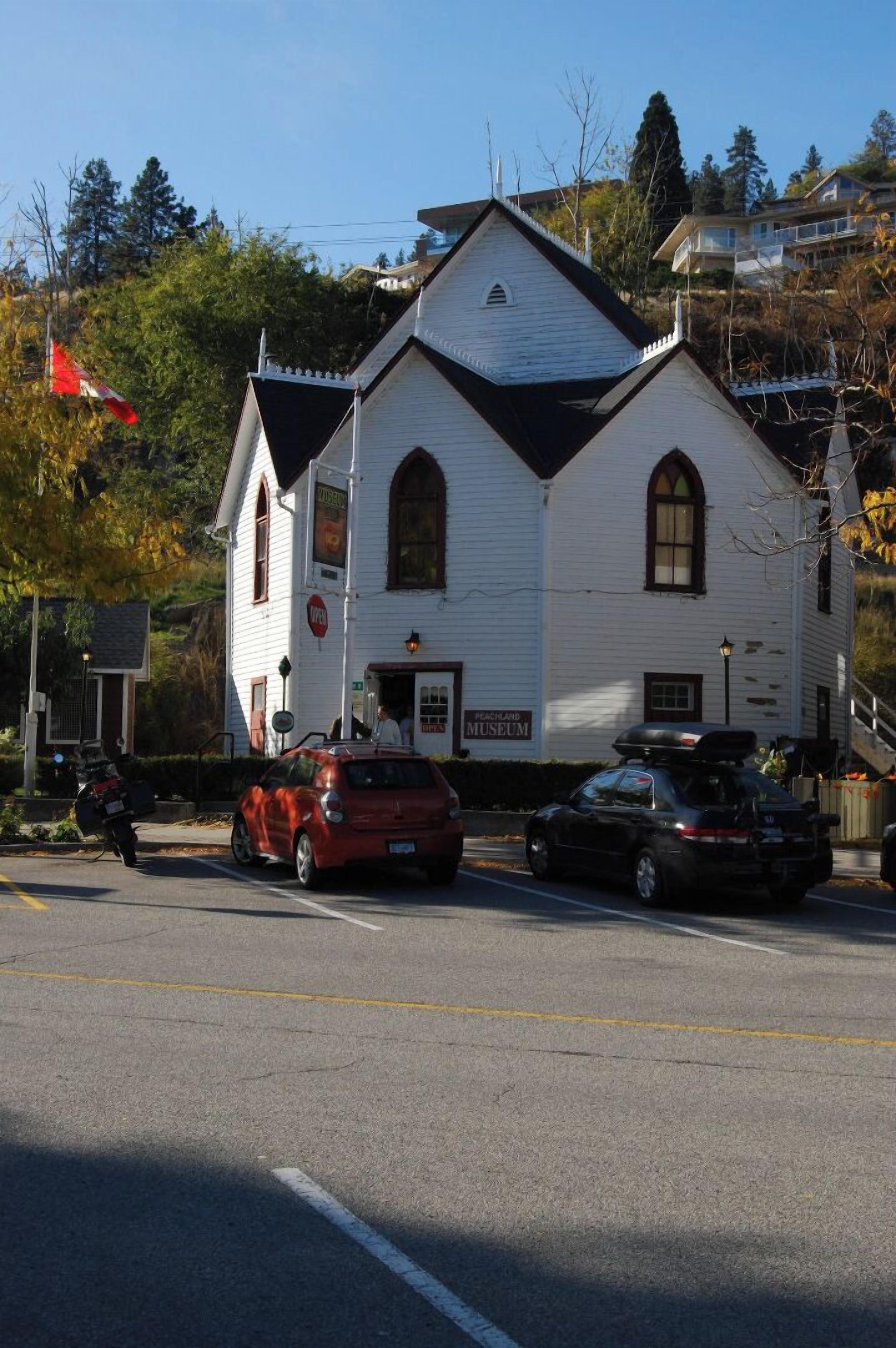 A white building with a sign for the Peachland Museum.