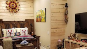 Ein gemütliches Wohnzimmer mit einer Couch, einem Couchtisch und einem Fernseher. Es gibt eine Holzeinrichtung und ein Bild an der Wand.