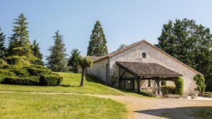 Un edificio rústico de piedra con techo de tejas, rodeado de vegetación exuberante y árboles altos.