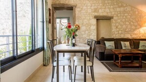 Un comedor con pared de piedra, una mesa con sillas y un sofá.