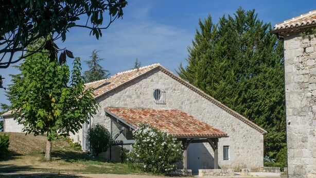 A stone building with a tiled roof, a small window, and a gravel driveway. - Gîte with swimming pool and park garden (Saint Maurin)