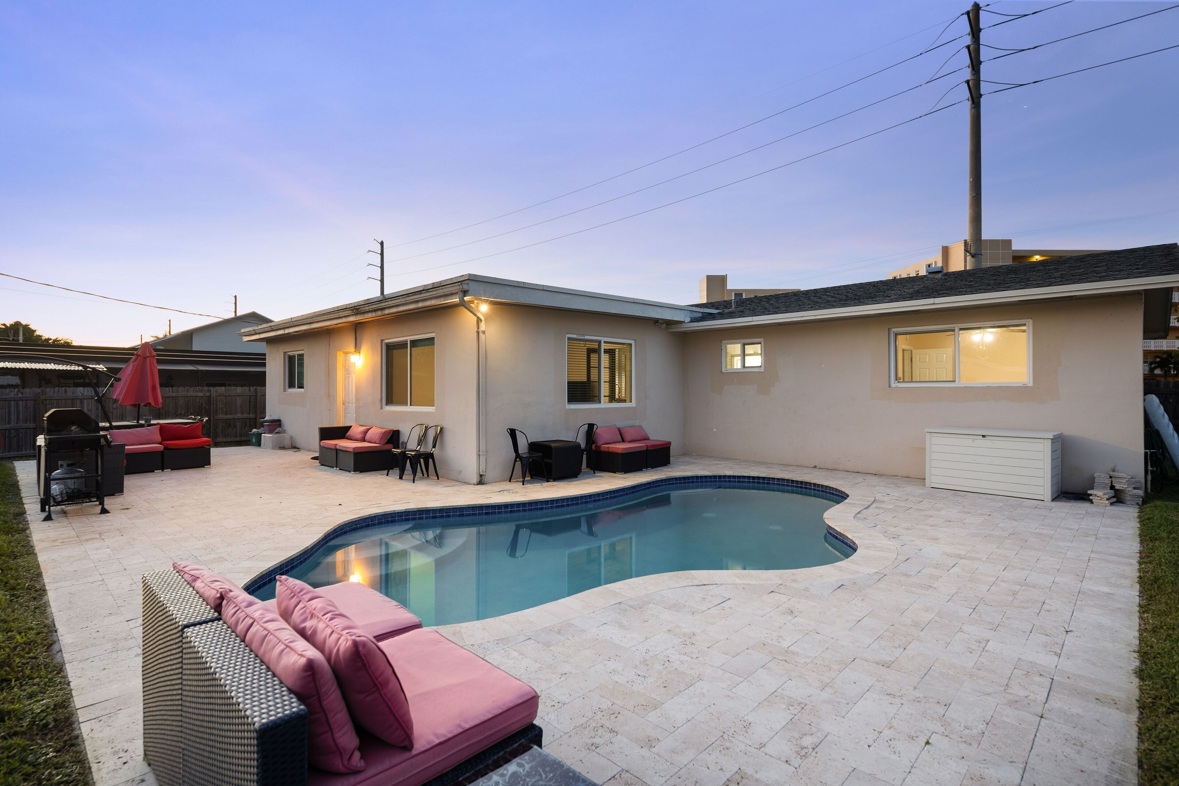 A backyard with a swimming pool, outdoor seating, and a house.