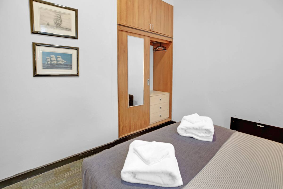 Ein Hotelzimmer mit einem Bett, einem Holzschrank, einem Spiegel und zwei gerahmten Bildern an der Wand.