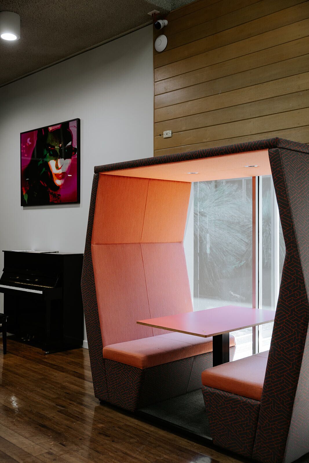 Een moderne kamer met een wand van houten panelen, een zwart piano en een kleurrijk abstract schilderij.