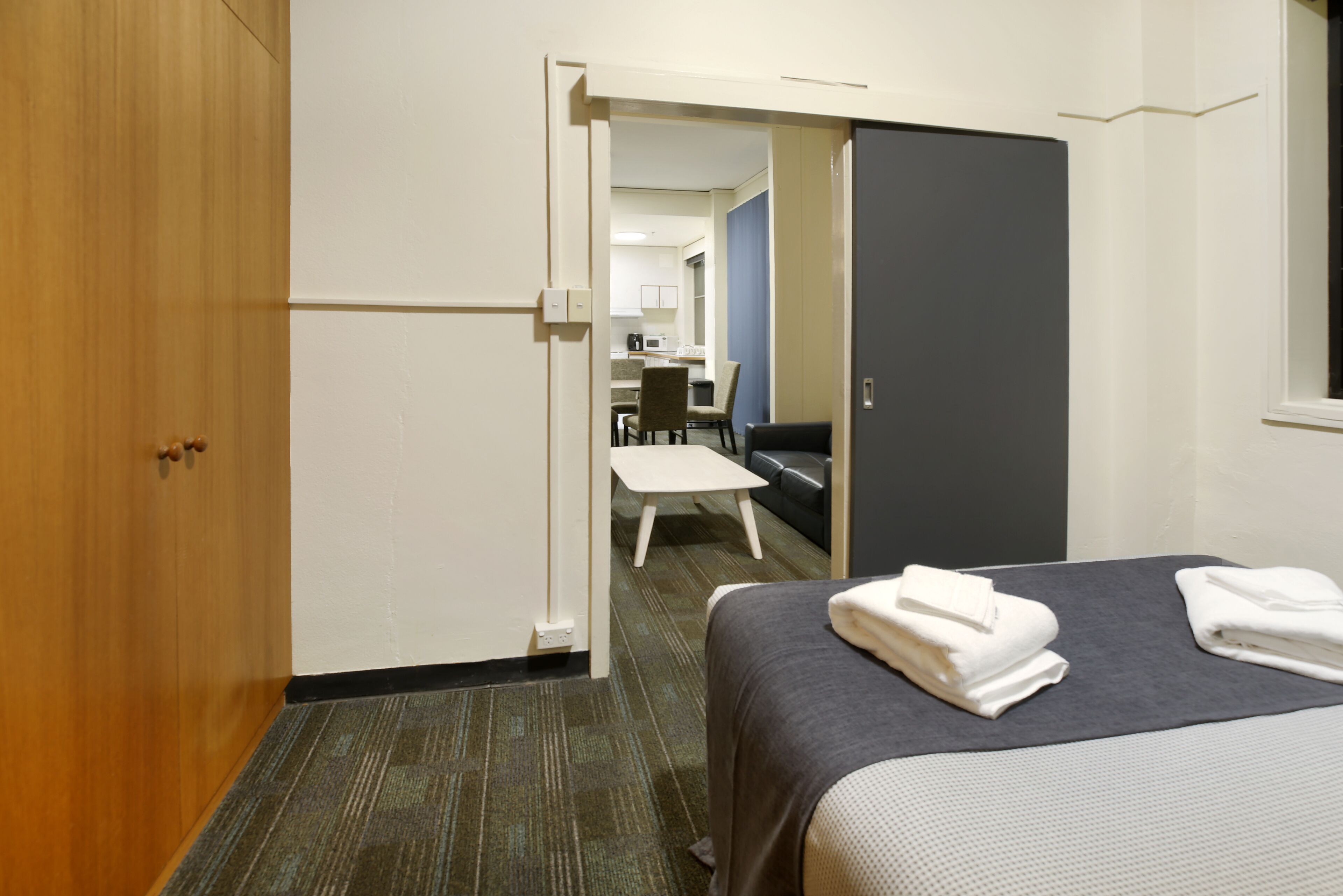 A hotel room with a bed, a desk, a chair, and a wardrobe.