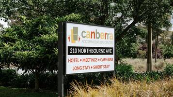 A sign for the Canberra Accommodation Centre at 210 Northbourne Ave, listing amenities like hotel, meetings, cafe/bar, and options for long stay or short stay.