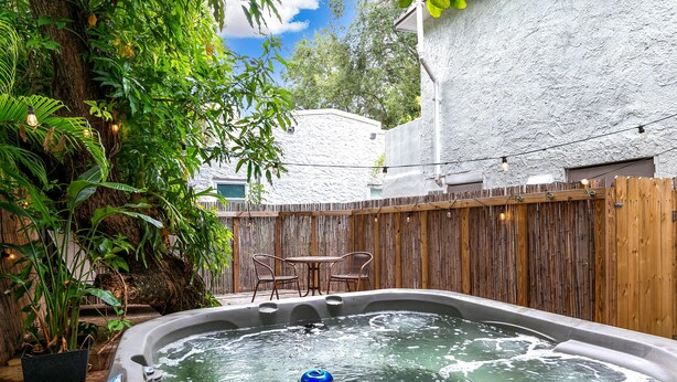 Een hottub omringd door een houten hek, met een tafel en stoelen in de buurt.