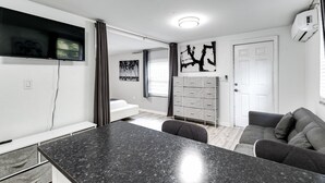 Een moderne woonkamer met een zwart granieten aanrechtblad, een grijze bank en een flatscreen televisie aan de muur.