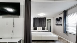 Een moderne slaapkamer met een bed, een aan de muur bevestigde televisie en een raam met zonwering.