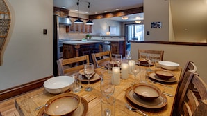 Un coin repas avec une table en bois dressée pour six personnes, entourée de chaises en bois.