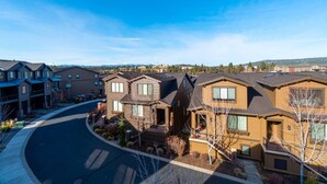 Un quartier résidentiel avec des maisons modernes, une route sinueuse et un ciel bleu dégagé.