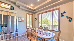 A dining area with a wooden table and chairs, a stainless steel refrigerator, and a window with blinds. - 'Doc's Retreat' in Ruidoso Downs w/ Mtn Views (Ruidoso Downs)