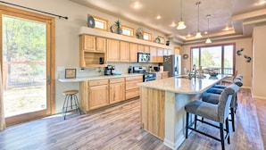 A spacious kitchen with wooden cabinets, a large island with bar stools, and a view of the outdoors. - 'Doc's Retreat' in Ruidoso Downs w/ Mtn Views (Ruidoso Downs)