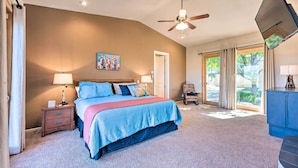 A bedroom with a bed, nightstands, a ceiling fan, a painting, and a view of the outdoors. - 'Doc's Retreat' in Ruidoso Downs w/ Mtn Views (Ruidoso Downs)