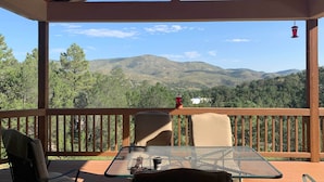 A covered outdoor seating area with a table and chairs, overlooking a mountainous landscape. - 'Doc's Retreat' in Ruidoso Downs w/ Mtn Views (Ruidoso Downs)