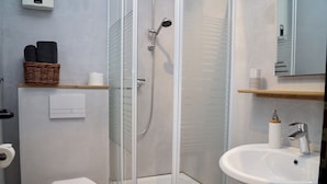 Ein modernes Badezimmer mit einer gläsernen Dusche, einem weißen Waschbecken und einer Toilette.