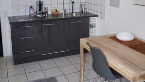 Eine moderne Küche mit dunklen Schränken, einer weißen Fliesenspiegel und einem Edelstahl-Spülbecken, sowie einem Holztisch mit einer Schüssel.