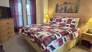 Una camera da letto con un letto grande, una cassettiera, una televisione e un affresco sulla parete.
