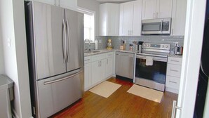 A modern kitchen with white cabinets, stainless steel appliances, and wooden flooring. - Downtown Silver Spring Ranch home! (Silver Spring)