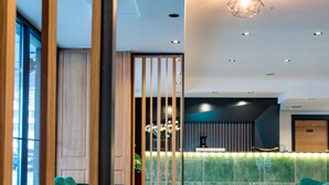 A modern interior with green upholstered seating, a wooden partition, and recessed lighting. - Ador Hotel (Pristina)