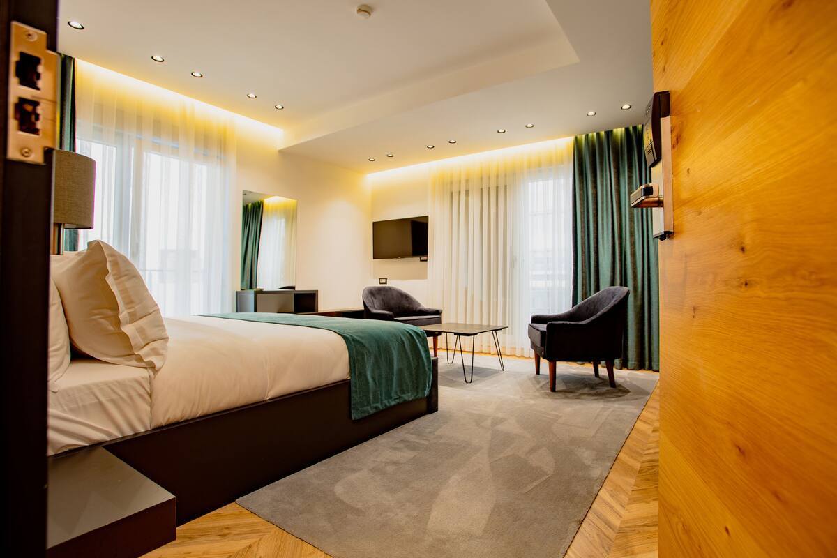 A modern hotel room with a bed, a desk, a chair, and a TV.