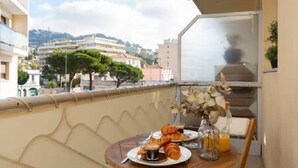 Un balcon avec une table préparée pour le petit-déjeuner, comprenant des croissants, du café et du jus d’orange.