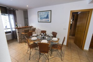 Un coin repas avec une table ronde en verre, des chaises en osier et une cheminée en briques.