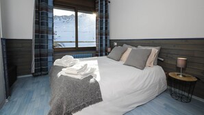 Une chambre à coucher avec un lit, une table de chevet, une lampe et une fenêtre avec des rideaux.