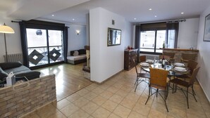 Un vaste espace de vie comprenant un canapé, une table à manger pour quatre personnes et un coin cuisine avec une table et des chaises.