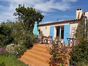 Una casa amb un pati, mobles d'exterior i una porta blava.