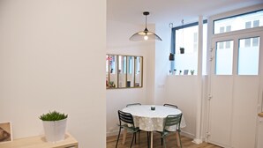 Un comedor con una mesa redonda, sillas, una lámpara colgante y un espejo en la pared.