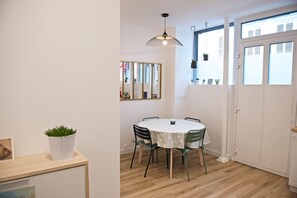 A dining area with a round table, chairs, a hanging pendant light, and a mirror on the wall.