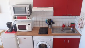 Eine kleine Küche mit Mikrowelle, Toaster, Kaffeemaschine, Spüle und Waschmaschine.