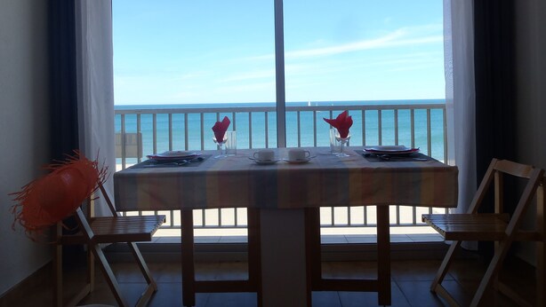 Ein Balkon mit Tisch für zwei Personen, mit Blick auf das klare, blaue Meer.