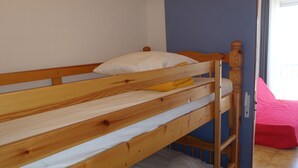 Ein Etagenbett mit Holzrahmen, einem weißen Kissen und einem gelben Handtuch im oberen Bett.