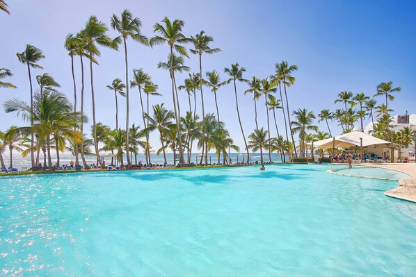 A pool area with palm trees and a view of the ocean.