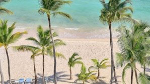 A beach with palm trees, blue lounge chairs, and a tent. - Beachfront  w/ View •Luxury •Smart TV • Gym (Juan Dolio)
