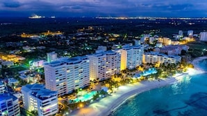 A coastal hotel with multiple high-rise buildings, a beachfront, and a swimming pool. - Beachfront  w/ View •Luxury •Smart TV • Gym (Juan Dolio)