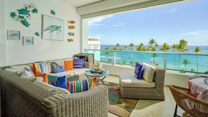A balcony with wicker furniture, a glass table, and a view of the ocean. - Beachfront  w/ View •Luxury •Smart TV • Gym (Juan Dolio)