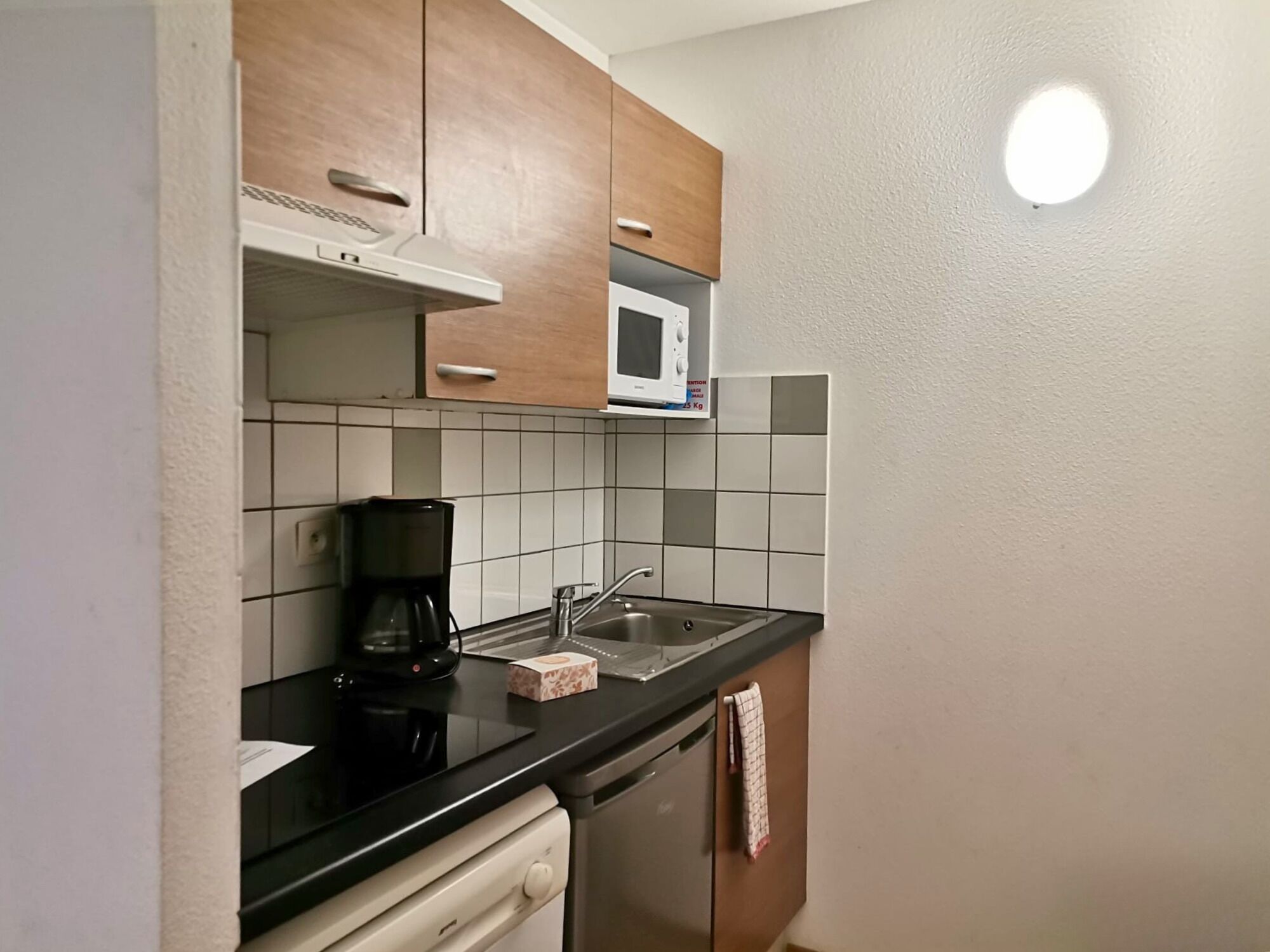 A compact kitchen with a microwave, coffee maker, and a small sink.