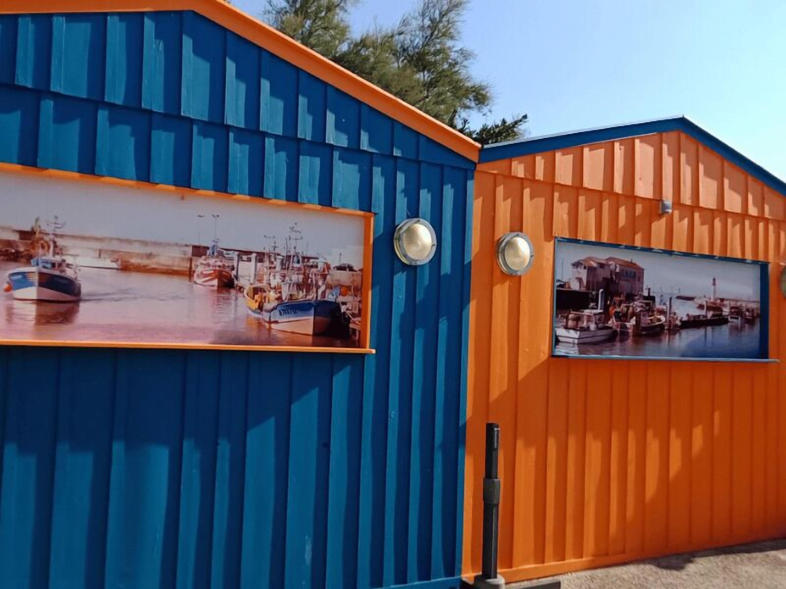 Een gebouw met twee grote ramen waarop scheepsschilderingen te zien zijn.