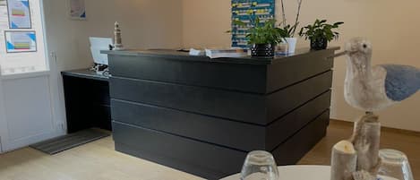 A reception desk with a 'Welcome' sign, a plant, and a decorative bird sculpture.