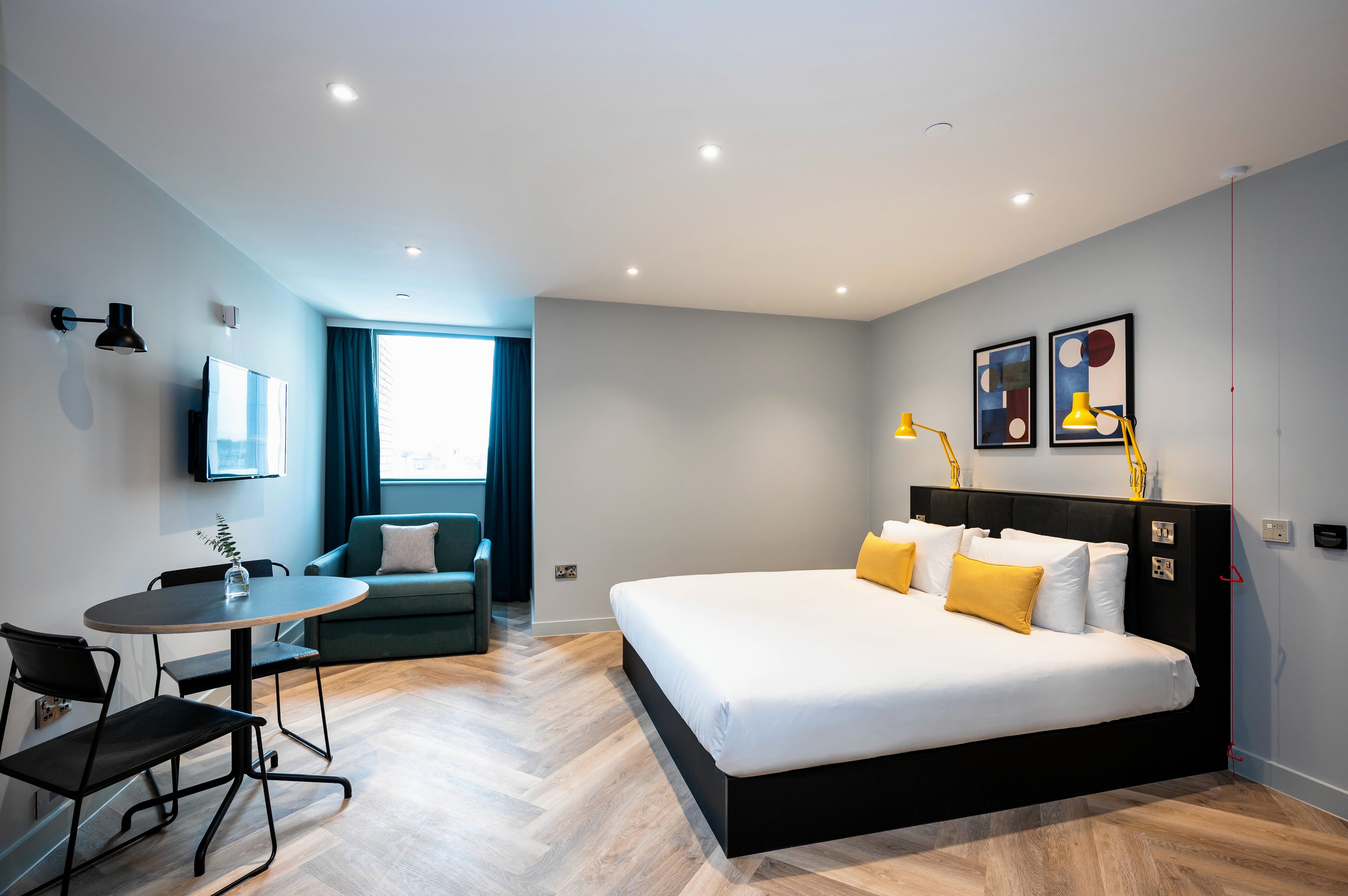 A modern hotel room with a large bed, a desk, and a sofa.