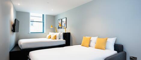 A modern hotel room with two beds, a desk, a chair, a TV, and a window.