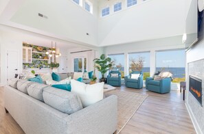 A spacious living room with a large gray sofa, blue armchairs, and a fireplace.
